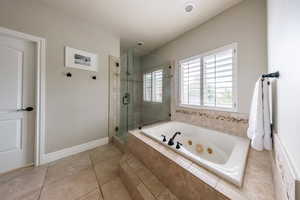 Full bathroom featuring a stall shower, a jetted tub, tile patterned floors, and baseboards