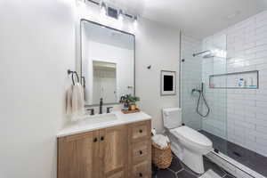 Bathroom featuring walk in shower, toilet, vanity, and baseboard heating