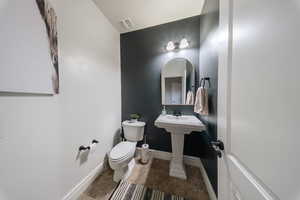 Bathroom with toilet, tile patterned flooring, and baseboards