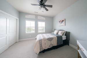 Bedroom featuring light colored carpet, baseboards, ceiling fan, and a closet