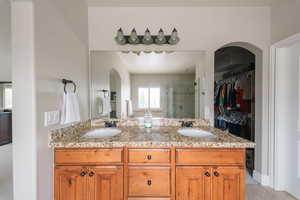 Bathroom featuring a shower stall, a spacious closet, and double vanity