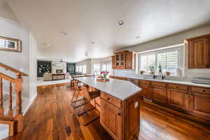 Kitchen featuring brown cabinets, a sink, light countertops, a breakfast bar, and open floor plan