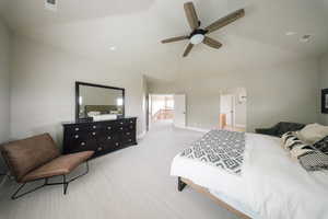 Carpeted bedroom with arched walkways, ensuite bathroom, baseboards, a ceiling fan, and high vaulted ceiling