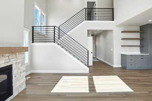 Unfurnished living room with a high ceiling, stairs, wood finished floors, and a fireplace