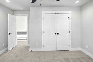 Unfurnished bedroom with carpet, recessed lighting, a closet, and a ceiling fan