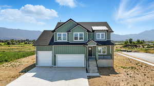 Craftsman-style home featuring a mountain view, driveway, roof with shingles, and board and batten siding