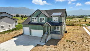 View of front facade with board and batten siding, roof with shingles, a mountain view, and driveway