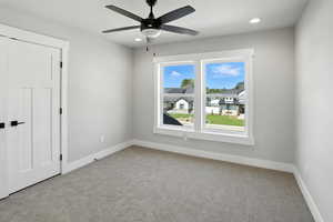 Carpeted spare room with a ceiling fan and recessed lighting