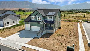 View of front facade featuring roof with shingles, driveway, board and batten siding, a mountain view, and a garage