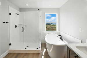 Full bath with wood finished floors, a freestanding tub, a marble finish shower, vanity, and recessed lighting