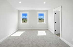 Primary suite featuring recessed lighting, light carpet, and plenty of natural light