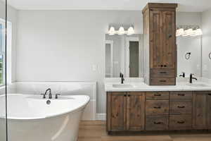 Bathroom with wood finished floors, a freestanding bath, and double vanity