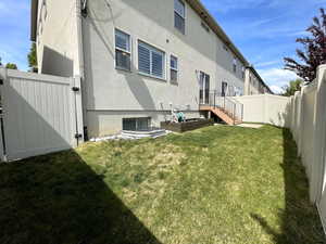 Rear view of house featuring stucco siding and a gate
