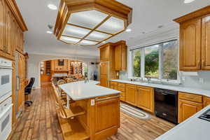 Kitchen featuring dishwasher, crown molding, arched walkways, light countertops, and light wood-style floors