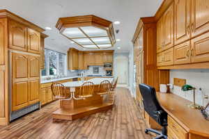 Kitchen featuring light countertops, ornamental molding, stainless steel microwave, hardwood / wood-style flooring, and a kitchen island with sink
