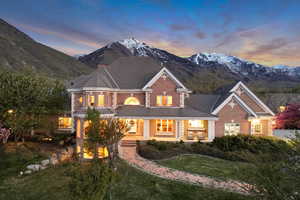 View of front facade featuring a tiled roof, a mountain view, brick siding, and a front lawn
