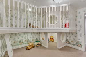 Detailed view of carpet, baseboards, a textured ceiling, wallpapered walls, and crown molding