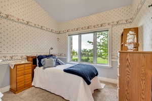 Bedroom featuring wallpapered walls, carpet, and lofted ceiling