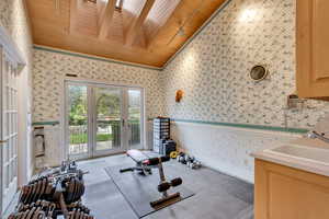 Workout room with wallpapered walls, wood ceiling, vaulted ceiling, and a sink