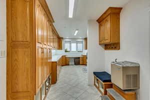 Kitchen featuring light tile patterned floors, brown cabinets, light countertops, and dishwashing machine