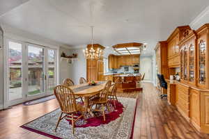 Dining area with hardwood / wood-style flooring, a chandelier, crown molding, and a desk