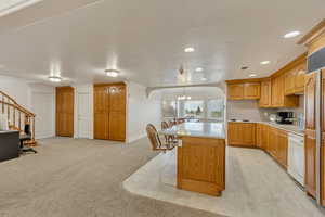 Kitchen featuring white dishwasher, a chandelier, light countertops, a center island, and recessed lighting