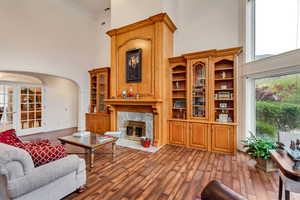 Living area featuring a high ceiling, arched walkways, a fireplace, dark wood-style flooring, and crown molding