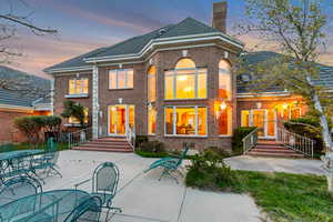 Back of property featuring a chimney, brick siding, a patio, and a tile roof
