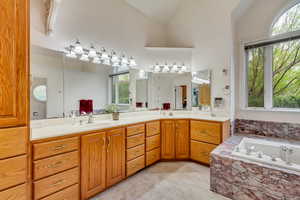 Full bathroom with a garden tub, double vanity, high vaulted ceiling, and tile patterned floors