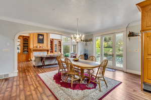 Dining room featuring a chandelier, ornamental molding, arched walkways, wood-type flooring, and baseboards