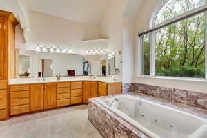 Full bathroom with lofted ceiling, a whirlpool tub, and double vanity