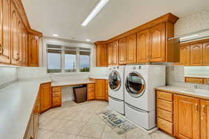 Laundry area featuring cabinet space, washing machine and dryer, light tile patterned floors, and wallpapered walls