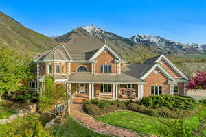 View of front of home featuring a tile roof, brick siding, a porch, and a mountain view