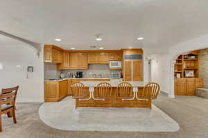 Kitchen featuring paneled fridge, white microwave, crown molding, arched walkways, and light countertops