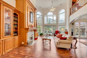 Living area with ceiling fan, a towering ceiling, a tiled fireplace, crown molding, and arched walkways