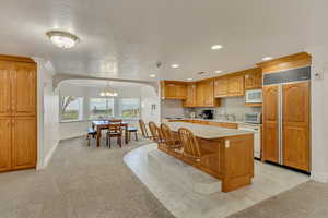 Kitchen featuring built in appliances, light countertops, light carpet, a chandelier, and recessed lighting