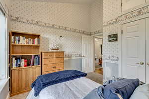 Bedroom with wallpapered walls and light carpet