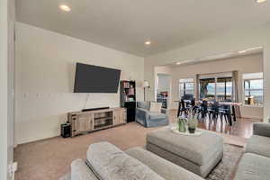 Living room with recessed lighting, a textured ceiling, baseboards, and light carpet