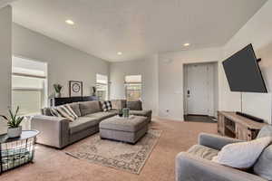 Living room with light carpet, recessed lighting, a textured ceiling, and baseboards