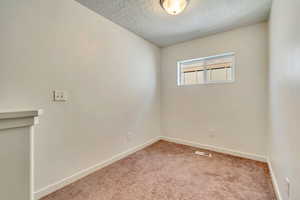 Unfurnished room featuring a textured ceiling, baseboards, and carpet