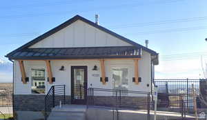 View of front of house featuring fence, a standing seam roof, a porch, board and batten siding, and stone siding