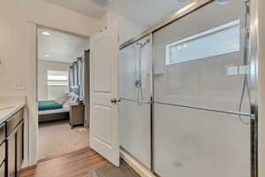 Full bathroom featuring wood finished floors, a stall shower, ensuite bath, and vanity