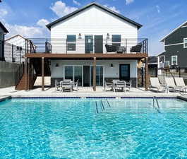Back of house featuring a balcony, stairs, fence, and a patio