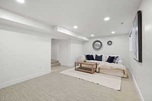 Living area with light carpet, recessed lighting, baseboards, and stairs