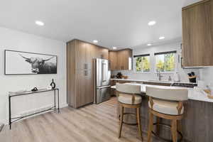 Kitchen featuring freestanding refrigerator, a peninsula, a sink, a kitchen breakfast bar, and recessed lighting