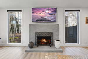 Detailed view of wood finished floors and a warm lit fireplace