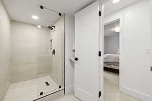 Bathroom featuring connected bathroom, a tile shower, baseboards, and recessed lighting