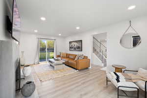 Living room with wood finished floors, stairway, recessed lighting, and baseboards