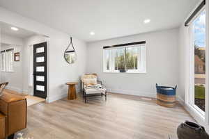 Sitting room featuring light wood-style floors, plenty of natural light, baseboards, and recessed lighting