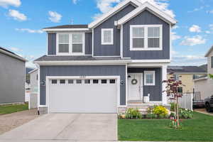 View of front driveway, flower garden, and a garage